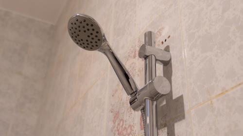 a shower with a shower head in a bathroom at بيت الشّاب in Ţīwī