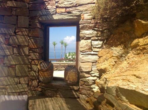 a window in a stone wall with palm trees in the background at Villa Aqua Marina in Vourkarion