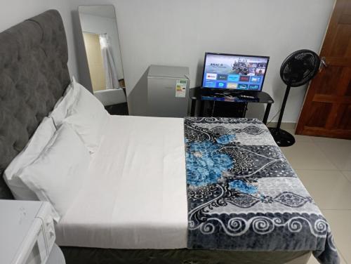 een bed in een kamer met een computermonitor bij The trout Lodge in Kaapstad