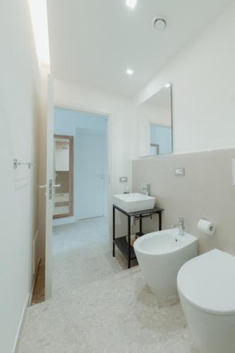 a white bathroom with a toilet and a sink at Verga 16 Deluxe Cefalù Apartments in Cefalù