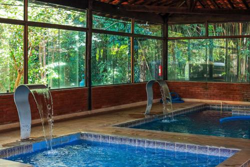 a pool with two faucets in a room with windows at Hotel Fazenda Campo dos Sonhos in Socorro
