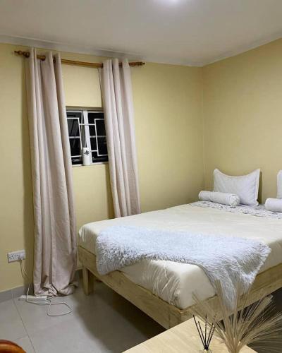 a bedroom with a bed with white sheets and curtains at Fal's Guesthouse in Lilongwe