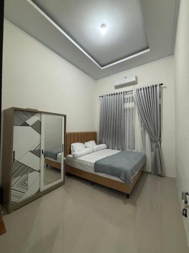 une chambre avec un lit et un miroir dans l'établissement Bundarooms Homestay Mibo, à Geutieue