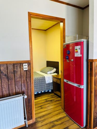 Una pequeña habitación con un refrigerador rojo y una cama. en Casa, en Punta Arenas