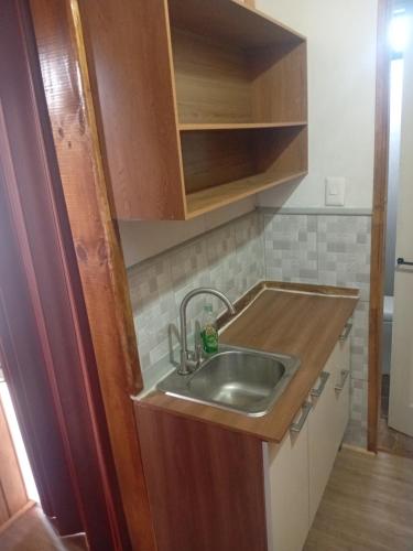 eine Küche mit Spüle und Holzschränken in der Unterkunft Alojha Coliumo Dichato in Coliumo