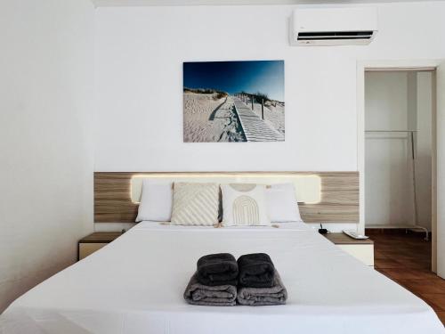 a bedroom with a white bed with two pairs of shoes at Alojamiento Vacacional con balcón La Vela in Puerto Calero