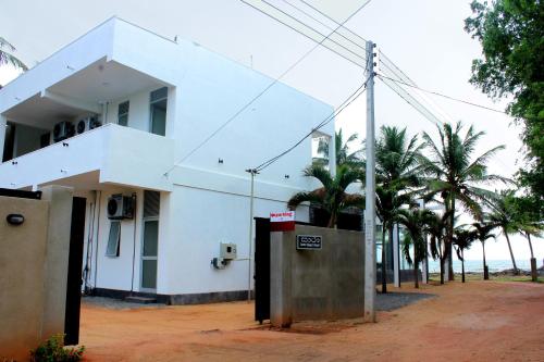 a white building with palm trees in front of it at Saara Beach Hotel in Marawila