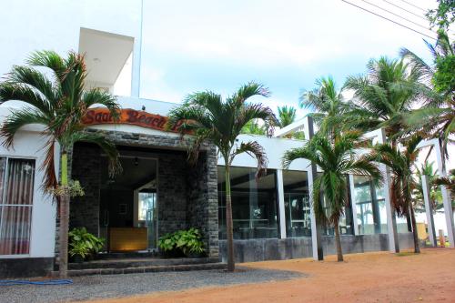 a building with palm trees in front of it at Saara Beach Hotel in Marawila