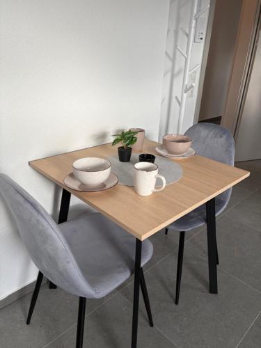 a wooden table with four chairs and cups on it at FeWo Mitte in Kettig