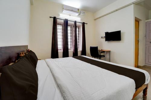 a bedroom with a white bed and a television at Collection O Govt Engineering College Formerly Anby Plaza in Kazhakuttam