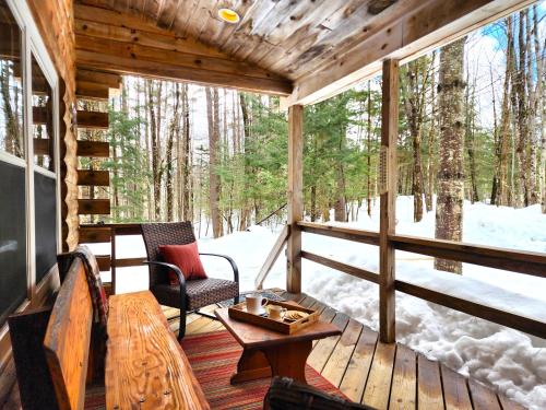 Stylish Forest Lodge with Large Hot Tub, Firepit and Fireplace minutes to Gore Mountain في North Creek: شرفة كابينة مع طاولة وكراسي