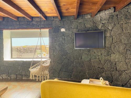 a room with a stone wall with a tv and a swing at Canaryislandshost I Viñedos in Uga