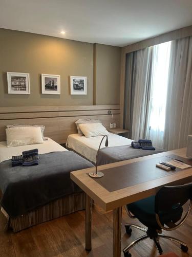 a hotel room with two beds and a desk with a desk at Flat Executivo Intercity Manaus - Moderno e Aconchegante in Manaus
