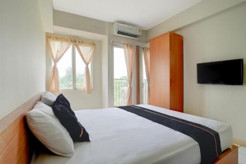 een slaapkamer met een bed, een televisie en een raam bij OYO 94837 Apartment Ekki Tower in Tjikuda Dua