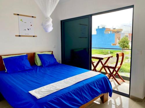una camera da letto con un letto blu con un tavolo e un balcone di Casa Uta a Tarrafal