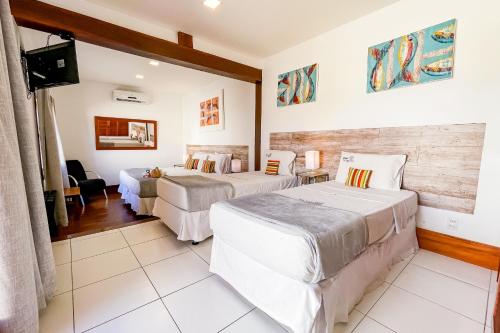 a hotel room with two beds and a television at Pousada Villegaignon in Búzios