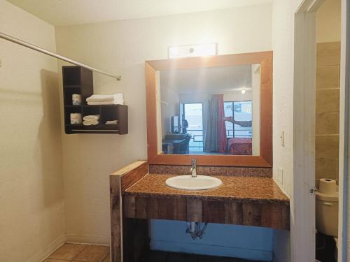 a bathroom with a sink and a mirror at Sunset Inn by Hotel O Flatonia I - 10 in Flatonia
