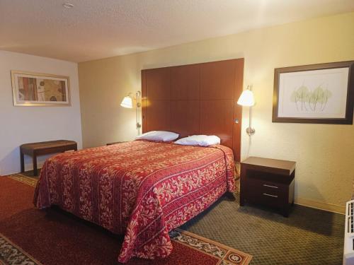 a hotel room with a bed with a red blanket at Sunset Inn by Hotel O Flatonia I - 10 in Flatonia