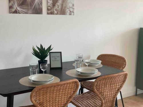 a black table with chairs and plates and glasses at cozy Apartment I WLAN in Neustadt in Neustadt in Sachsen