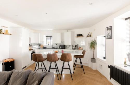 a white kitchen with a table and stools at Entire house, close to central Bristol in Bristol
