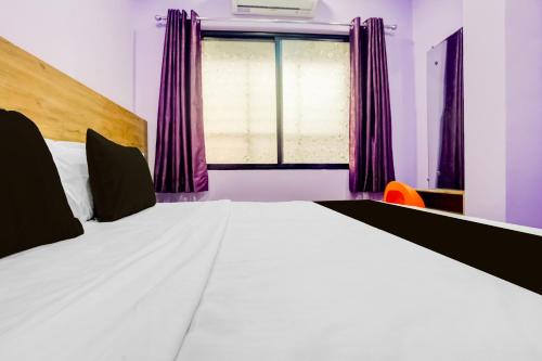 a bedroom with a large bed with purple curtains at Hotel O Nashik Road Railway Station in Deolāli