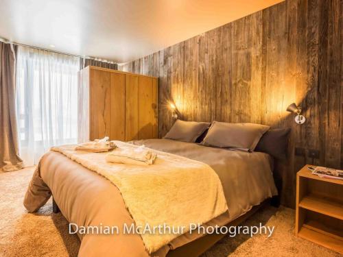 a bedroom with a large bed with a wooden wall at Loft Amenda, duplex d'exception pour 12 personnes et 7 pièces - FR-1-314-305 in Avoriaz