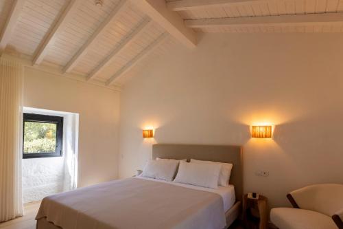 a bedroom with a white bed and a chair at Casa das Costinhas in Loureda