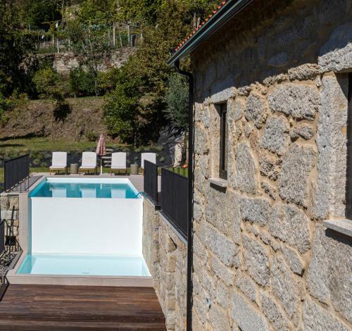 a pool in a stone wall next to a house at Casa das Costinhas in Loureda