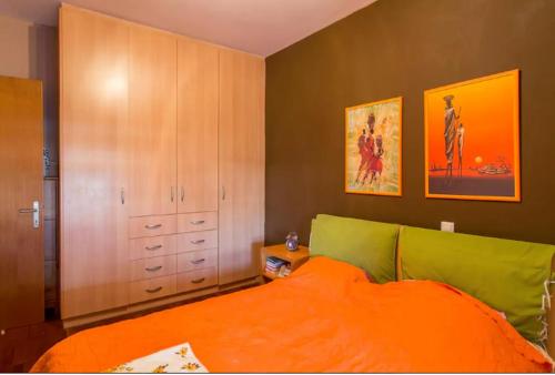 ein Schlafzimmer mit einem Bett mit einer orangefarbenen Decke in der Unterkunft Apartment by the Airport in Koropi