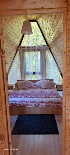 a bed in a small room with a window at Cabana A-FRAME 3 in Curtea de Argeş