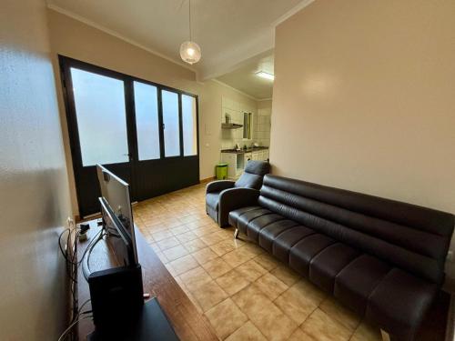 ein Wohnzimmer mit einer schwarzen Couch in einem Zimmer in der Unterkunft Sea View Madeira Machico 1 Bedrooms Terrace Villa in Ribeira Seca