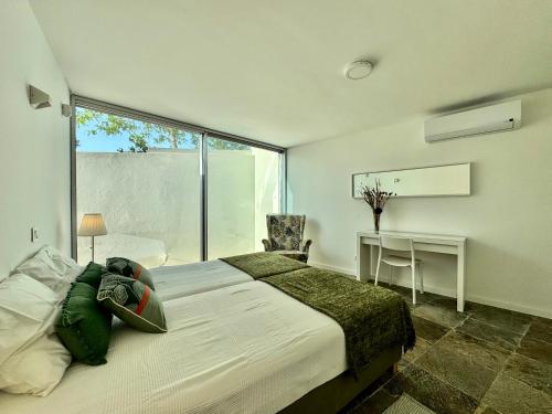 ein Schlafzimmer mit Bett, Schreibtisch und Fenster in der Unterkunft Casas do Moinho, Alentejo Country House in Santa Margarida da Serra
