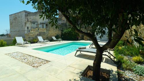 a swimming pool with two chairs and a tree at Dimora Zenieri – Terrazze & Piscina in Casarano