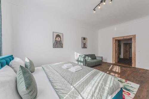 a white bedroom with a bed and a couch at Obrovský byt na Velkém náměstí, WiFi zdarma in Hradec Králové
