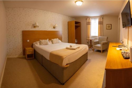 a hotel room with a large bed and a chair at Sturdy`s Castle - Historic Coaching Inn near Blenheim Palace, Oxfordshire in Woodstock