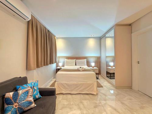 a hotel room with two beds and a couch at Studio Novo no Centro para 4 pessoas in Foz do Iguaçu