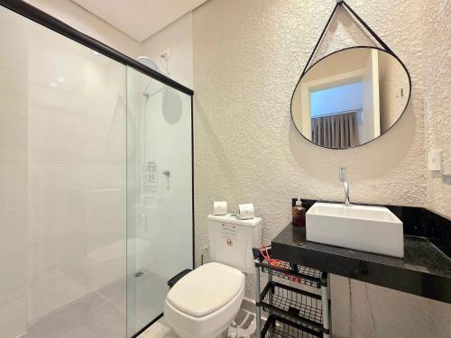 a bathroom with a toilet and a sink and a mirror at Studio Novo no Centro para 4 pessoas in Foz do Iguaçu