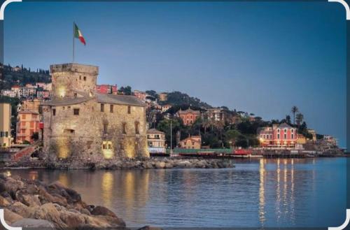 un vieux bâtiment avec un drapeau au-dessus d'une étendue d'eau dans l'établissement Casa Sirio -Rapallo, à Rapallo