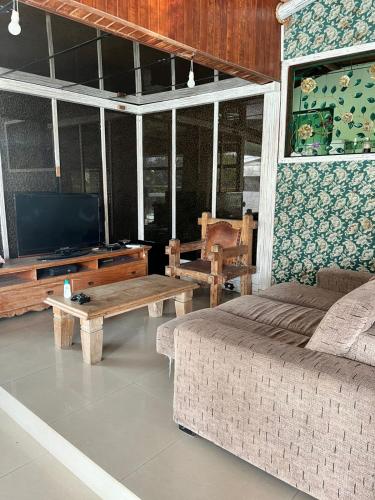a living room with a couch and a tv and a table at Ótima casa próxima a praia e o centro in Ilhabela