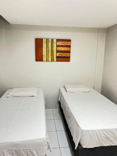 zwei Betten in einem Zimmer mit einem Gemälde an der Wand in der Unterkunft Hotel Visconde in Sobral