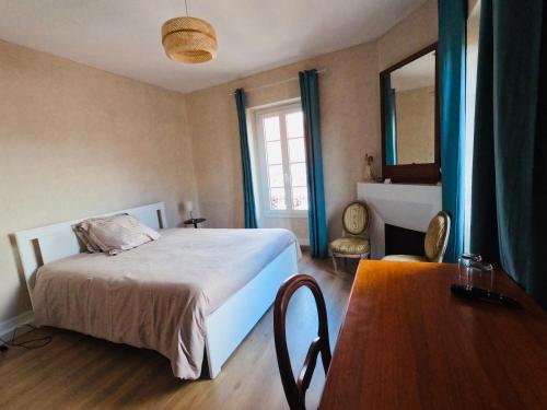 una camera da letto con un letto, un tavolo e uno specchio di Chambre privée dans maison de ville du XVIIIe siècle a Carbonne