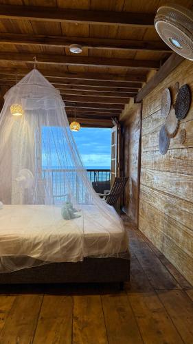 a bedroom with a bed with a mosquito net at El Almendrón Beach Hostel in Santa Marta