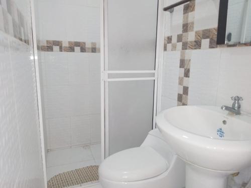 a white bathroom with a toilet and a sink at Hotel Villa Real Tolú in Tolú