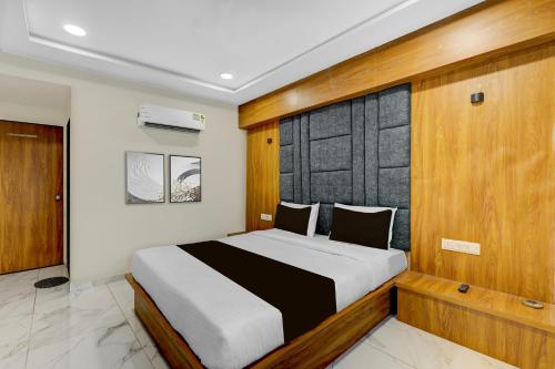 a bedroom with a large bed with a wooden headboard at Hotel O Anand guest house in Vastral