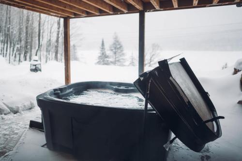 eine schwarze Wanne mit Fernseher im Schnee in der Unterkunft Lakeview Mid Century Luxury Cottage in Sainte-Adèle