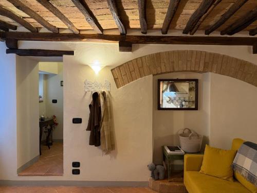 a living room with a yellow couch and a wall at Casina Gattoli in Montalcino