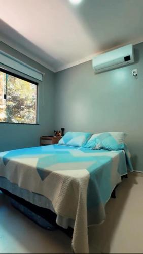 a blue bedroom with a bed with a window at Residencial Recanto dos Colibris in Porto Seguro