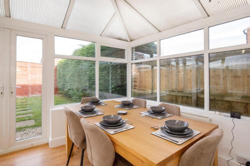 a dining room with a table and chairs and windows at Your Home Away From Home - Near York City Centre in York