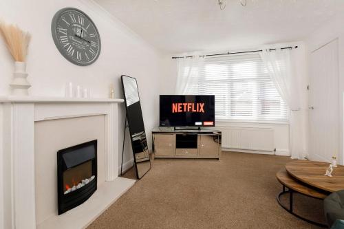 a living room with a tv and a clock on the wall at Your Home Away From Home - Near York City Centre in York