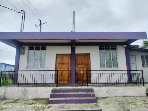 a small house with wooden doors and a fence at Adoreen Homestay in Cherrapunji